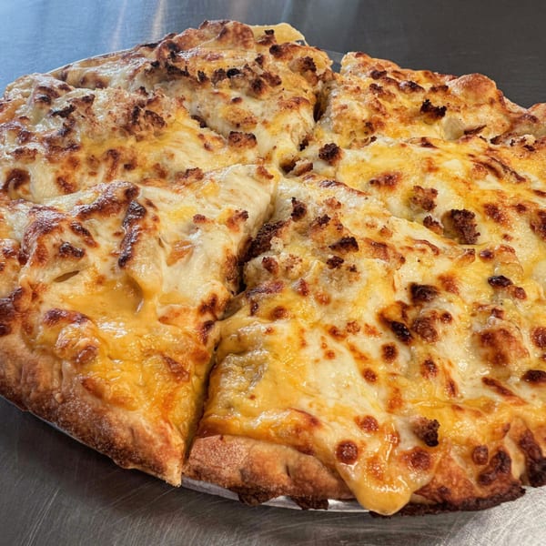 Close-up of a B Antonio's Pizza, cut into slices, with melted cheese and sausage.