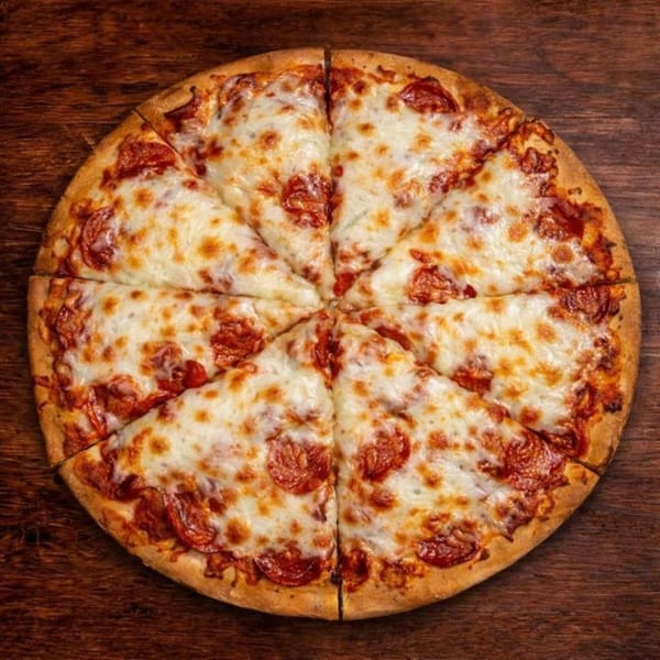 A whole pepperoni pizza, cut into eight slices, on a rustic wooden table.